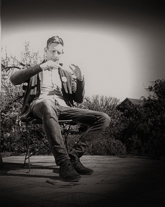 Philippe Ramakers sitzt im Garten und erklärt etwas mit beiden Händen